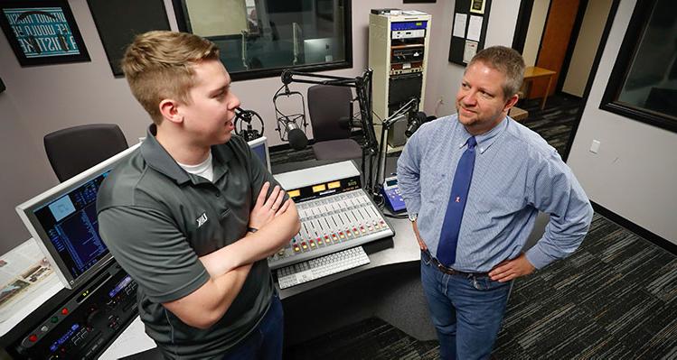 bet36365体育 Communication student in the campus radio station speaking to professor Ford Clark