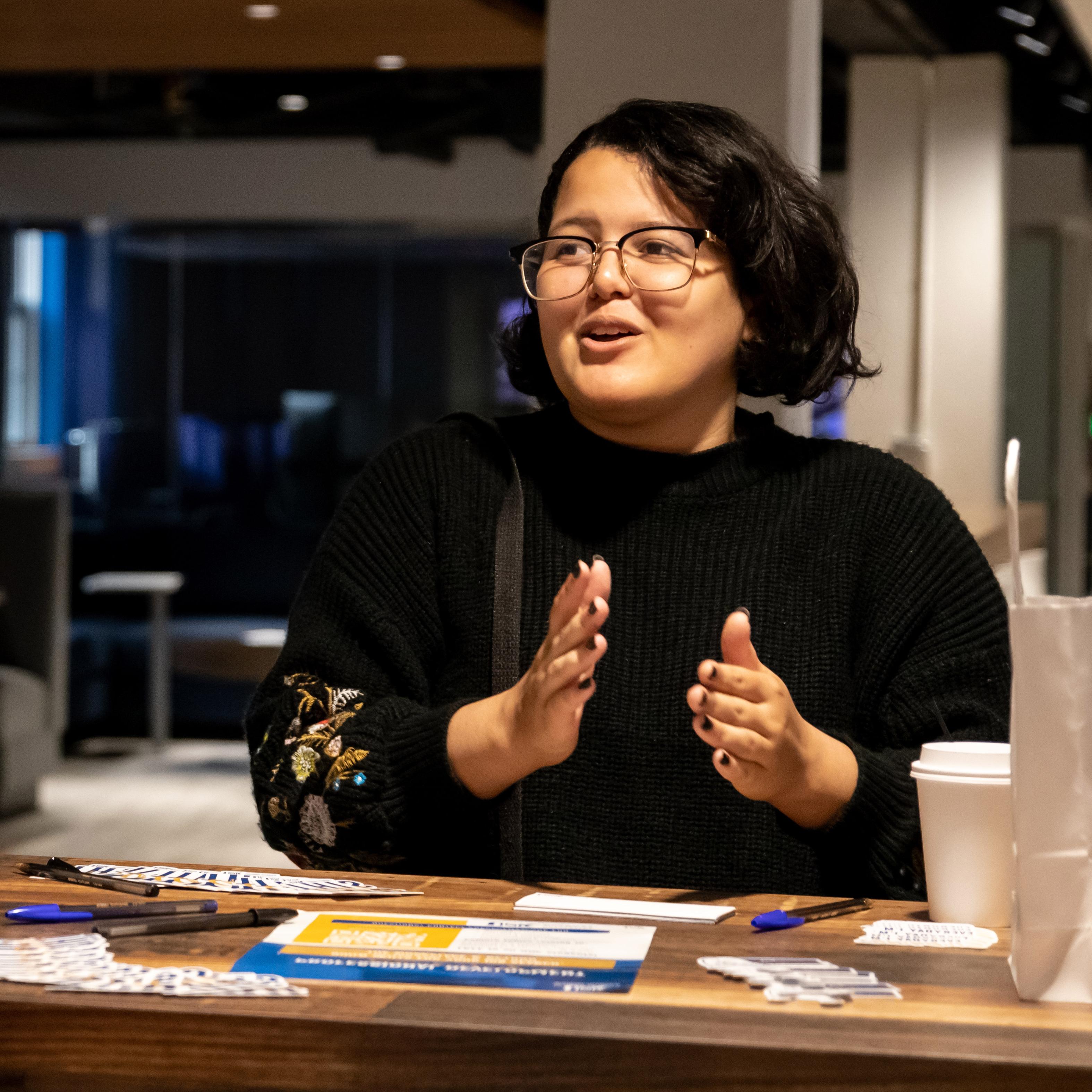 a student sits at a counter gesturing and speaking