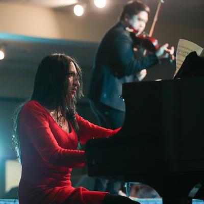 a woman in a red dress plays the piano during the FAME Talent show